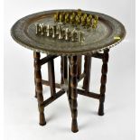 A Middle Eastern style tinned and copper circular tray-top table, with embossed chessboard centre,