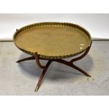 A large Eastern circular brass tray-top table with piecrust rim and incised foliate decoration,