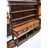 A George III oak dresser, the moulded cornice above boarded plate rack with three shelves,