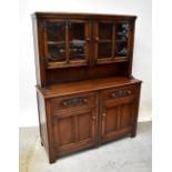 E GOMME; a carved oak dresser with a pair of glazed cupboards to the top,