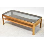 A 20th century teak coffee table, with smoky glass top and solid undershelf, on quarter cut legs,