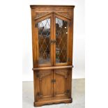 A reproduction oak glazed corner cupboard, the top with pair of leaded doors, within carved borders,