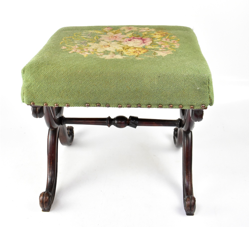 A Victorian mahogany X-framed footstool, with floral tapestry padded seat.