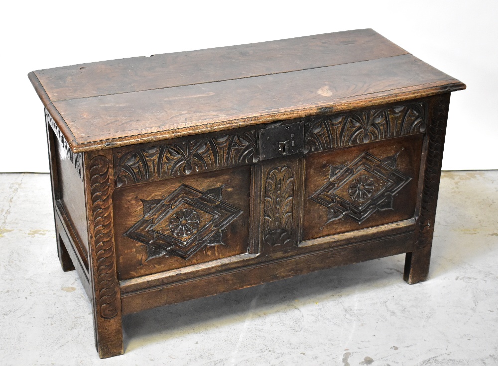 A Georgian oak panelled coffer with plank top and carved geometric and floral panels to the front,