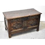 A Georgian oak panelled coffer with plank top and carved geometric and floral panels to the front,