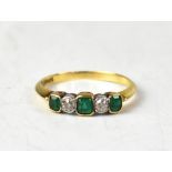 An 18ct yellow gold five-stone ring set with alternating emerald cut emeralds and rose cut diamonds,