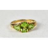 A 9ct gold three-stone peridot ring, the central marquise claw set stone flanked by claw set stone,