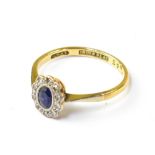 An 18ct yellow gold ring with central bezel sapphire within a flowerhead border of ten tiny