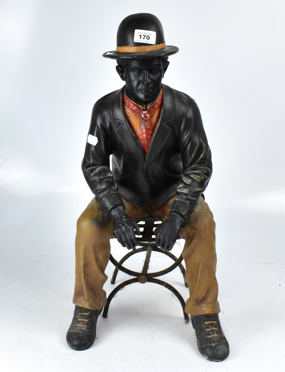 A decorative fibreglass figure of a seated gentleman upon a chair.