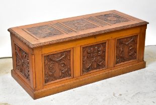 A reproduction oak bedding box with carved front panels of floral design,