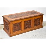 A reproduction oak bedding box with carved front panels of floral design,