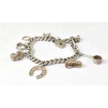 A sterling silver charm bracelet with various silver charms to include a well, a horseshoe,