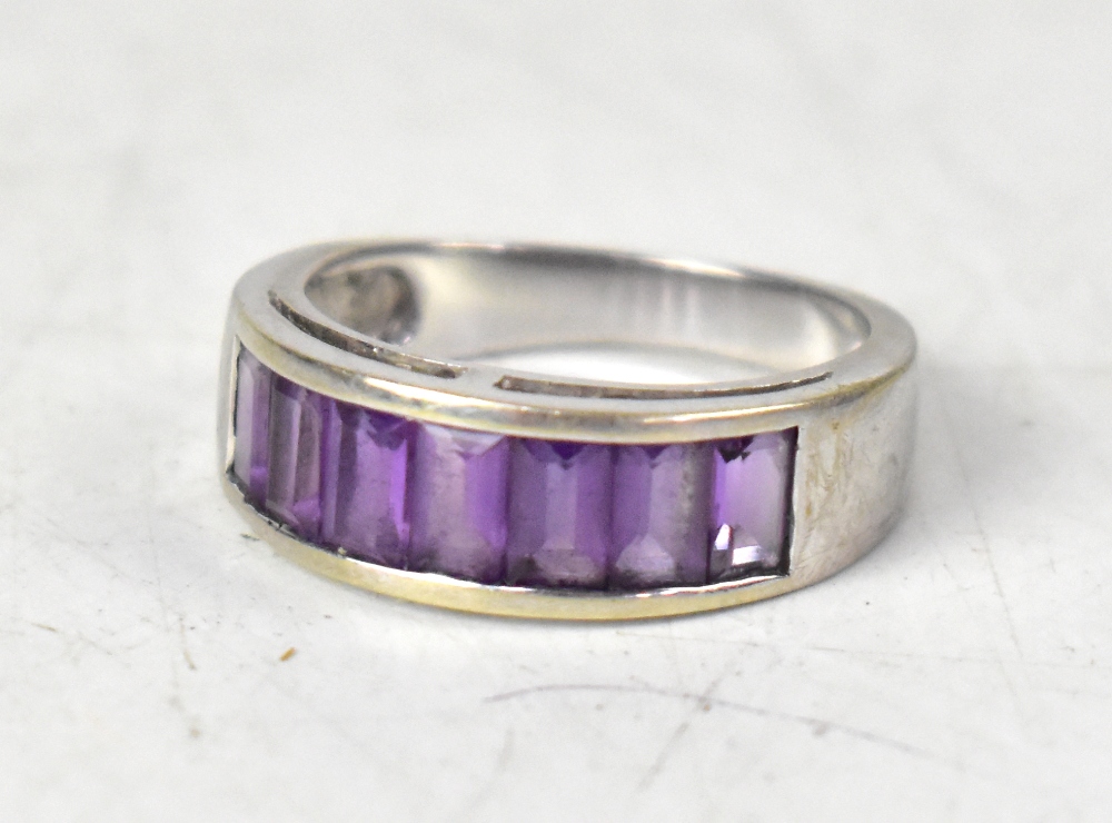 A modern 9ct white gold ring, pavé set with seven emerald cut amethyst stones, size O, approx 4.4g.