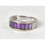 A modern 9ct white gold ring, pavé set with seven emerald cut amethyst stones, size O, approx 4.4g.