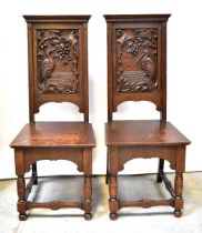 A pair of late Victorian carved oak hall chairs, each panelled back decorated with a stork,