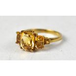 A 9ct yellow gold ring set with a central cushion cut citrine, flanked by two smaller oval citrines,
