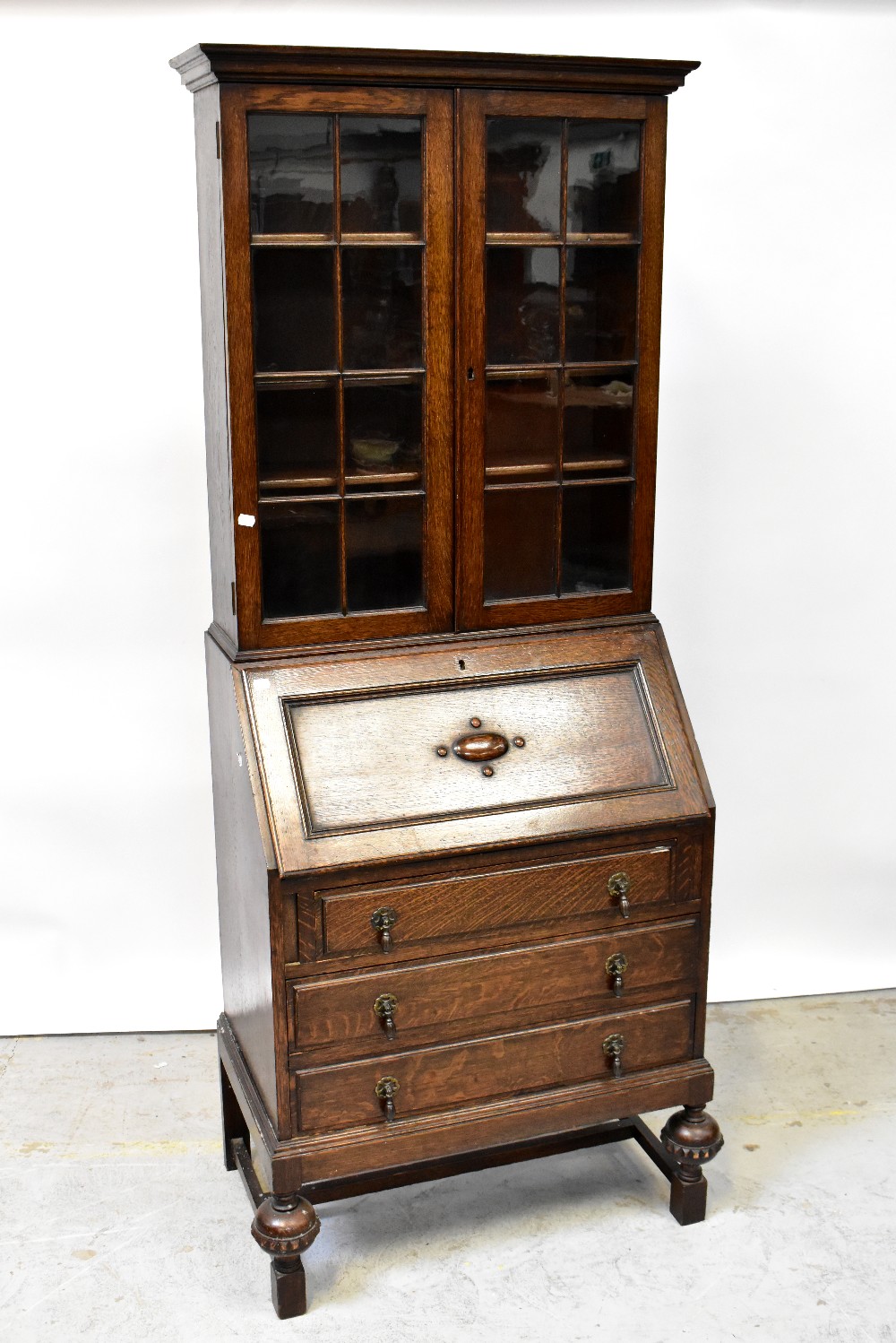 An early 20th century oak bureau bookcase, the moulded cornice above pair of glazed doors,