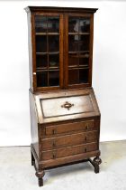 An early 20th century oak bureau bookcase, the moulded cornice above pair of glazed doors,