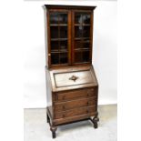 An early 20th century oak bureau bookcase, the moulded cornice above pair of glazed doors,