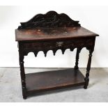 A Victorian carved oak side table with carved scrolling back above a single frieze drawer,