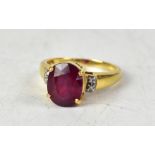 An 18ct ruby and diamond ring, the round cut Majestic stone with tiny chips to each shoulder,
