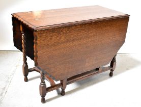 An early 20th century oak drop-leaf dining table with piecrust rim and barleytwist block