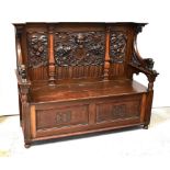A late Victorian carved oak box seat hall bench with stepped cornice above cherubic and shield