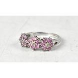 A 9ct white gold ring with three pink sapphire flowerheads, size N, approx 2.5g.