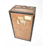 A vintage metal bound steamer trunk enclosing a fitted interior with wardrobe section to one side,