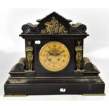 A late 19th century French black slate mantel clock with figural columns flanking the circular dial,