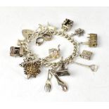A hallmarked silver charm bracelet with approximately fourteen silver charms, to include church,