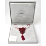 LALIQUE; a red glass pendant necklace in the form of an entwined snake,