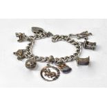 A sterling silver charm bracelet with various silver charms to include a tractor,