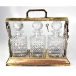 A late 19th/early 20th century three-bottle silver plated tantalus with lockable carry bracket,