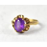 A yellow metal ring set with an oval amethyst in an open work floral mount, marks indistinct,