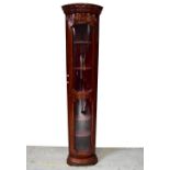 A contemporary mahogany freestanding glazed corner cabinet of narrow proportions,