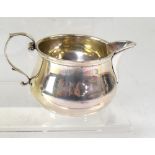 A George VI hallmarked silver milk jug of squat form, with scroll handle, Hardy Bros, Chester 1914,