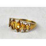 A 9ct gold diamond and citrine ring, the open mount holding five graduated citrines,