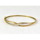 A modern 9ct gold bracelet with crossover ribbon design, one ribbon strand inset with tiny diamonds,