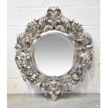 A large circular silvered wall mirror, the frame with Rococo-style scrolls and acanthus leaf motifs,