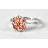 A 9ct white gold flowerhead ring, set with orange and white coloured sapphires,