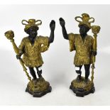 A pair of decorative bronzed and gilt metal figural candlesticks, raised on shaped plinths,