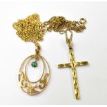 A gold oval pendant with pierced metal pattern and a small green jewel pendant,
