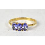 A 9ct yellow gold ring with three claw set oval tanzanite stones, size S, approx 2.1g.