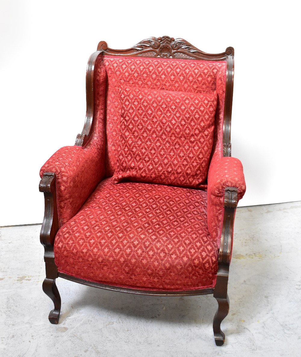 A reproduction walnut framed armchair with red upholstery and carved acanthus leaf decoration,