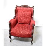 A reproduction walnut framed armchair with red upholstery and carved acanthus leaf decoration,