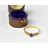 An Edwardian 18ct gold ring with prong set blue sapphire flanked by two oval shoulders with three