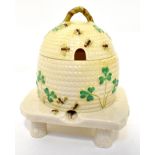 BELLEEK; a porcelain honey pot in the form of a bee hive with trailing shamrocks,