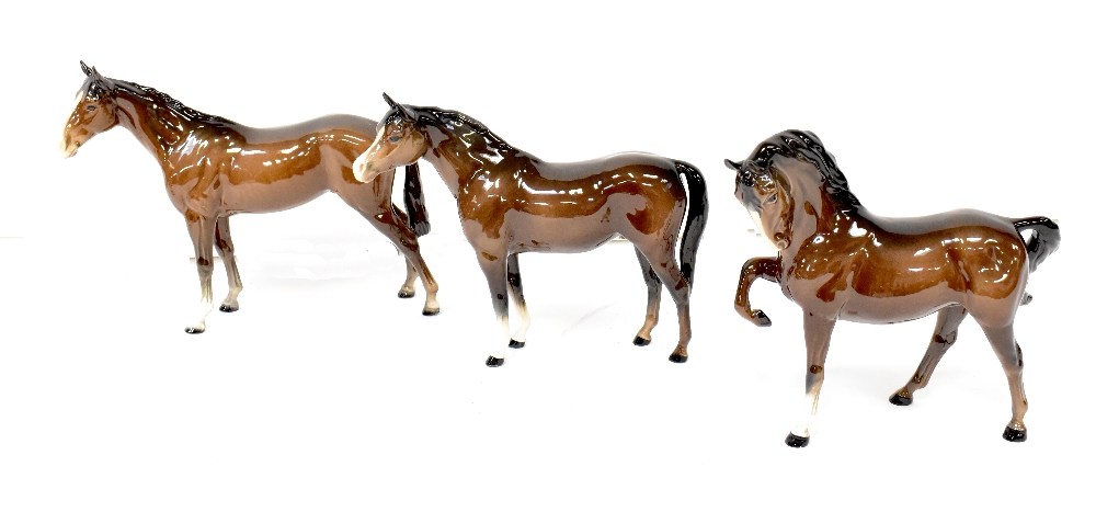 BESWICK; three gloss brown horses to include a racehorse second version, head tucked leg up,