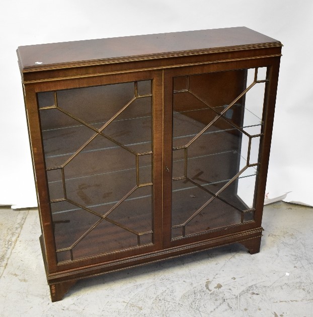 A reproduction mahogany display cabinet, the moulded top above a pair of astragal glazed doors,